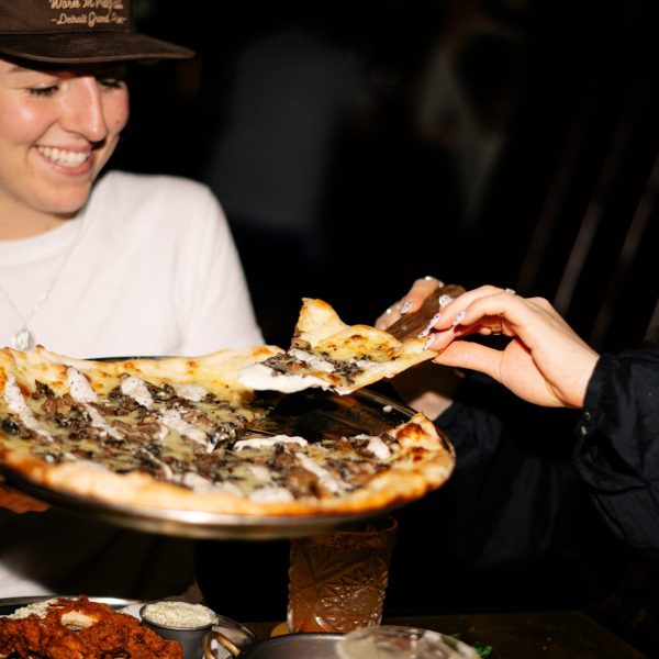 two friends sharing pizza and cocktails